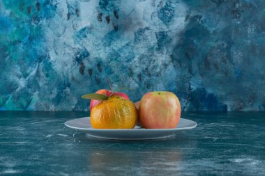 Kivi, mandalina ve elmalar bir tabakta, mermer arka planda. Yüksek kalite fotoğraf