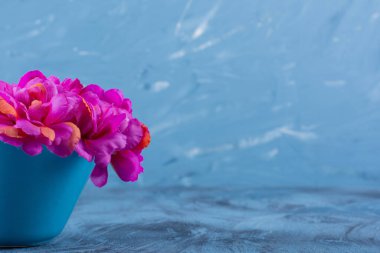 Mavi arka plandaki vazoda güzel mor çiçeklerin resmi. Yüksek kalite fotoğraf