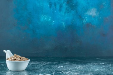 Mavi arka planda, kaşıkta kuru yulaf ezmesi. Yüksek kalite fotoğraf