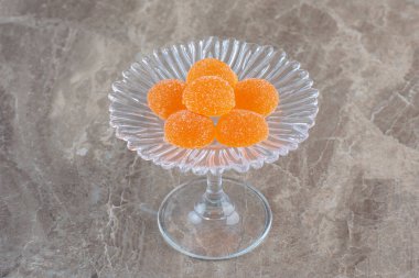 Gri arka planda cam tepside taze turuncu şekerler. Yüksek kalite fotoğraf