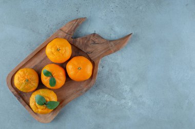Mandalina ve portakallar ahşap bir tepside, mermer arka planda. Yüksek kalite fotoğraf
