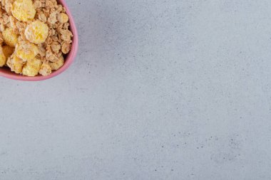 Gri arka planda lezzetli, sağlıklı mısır gevreği dolu pembe bir kase. Yüksek kalite fotoğraf