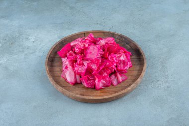 Mavi arka planda, ahşap bir tabakta kırmızı mayalanmış lahana turşusu. Yüksek kalite fotoğraf