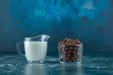 Mavi arka planda cam bir kasede mısır toplarının yanında bir bardak süt. Yüksek kalite fotoğraf