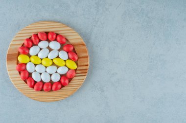 Beyaz arka planda yuvarlak renkli şekerlerle dolu ahşap bir tahta. Yüksek kalite fotoğraf