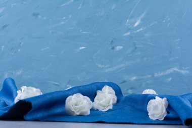 Beyaz gül yığını taştan arkaplandaki mavi kumaşın üzerine saçılmış. Yüksek kalite fotoğraf