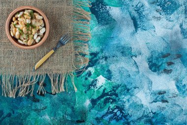 Mavi arkaplanda çatalın yanında bir kase beyaz fasulye. Yüksek kalite fotoğraf