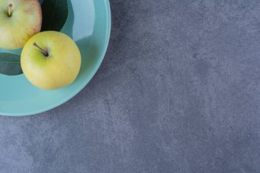 Mermer zemin üzerinde olgun elma ve yapraklardan oluşan bir tabak. Yüksek kalite fotoğraf