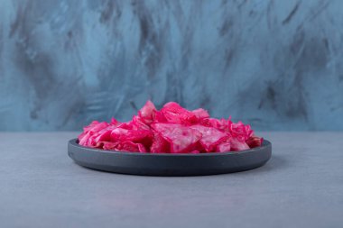 Mermer arka planda, tavada kırmızı lahana turşusu. Yüksek kalite fotoğraf