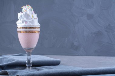 Bir bardak milkshake, üzerine şeker serpiştirilmiş krema serpiştirilmiş, mermer arka planda. Yüksek kalite fotoğraf