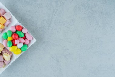 Beyaz arka planda lokum ve renkli şekerlerle dolu beyaz bir tahta. Yüksek kalite fotoğraf