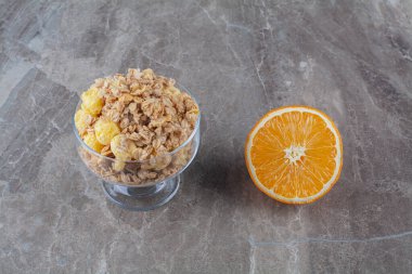 Bir bardak dolusu sağlıklı mısır gevreği ve bir dilim taze portakal meyvesi. Yüksek kalite fotoğraf