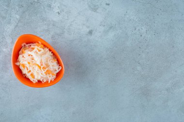 Mavi arka planda plastik kasede havuçlu mayalanmış lahana turşusu. Yüksek kalite fotoğraf