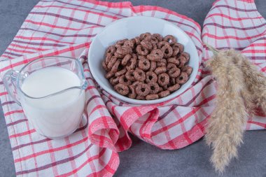 Bir bardak süt, cam bir kasede mısır halkasının yanında çay havlusundaki otların yanında, mermer arka planda. Yüksek kalite fotoğraf