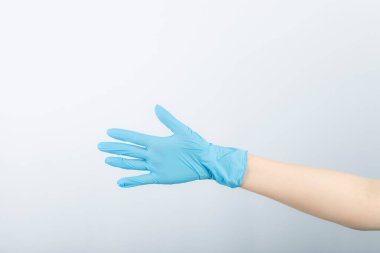 İnsan eli mavi lateks tıbbi eldiven giyiyor.