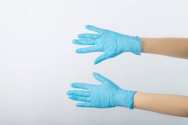 Beyaz arka planda cerrahi eldivenli doktor elleri var.