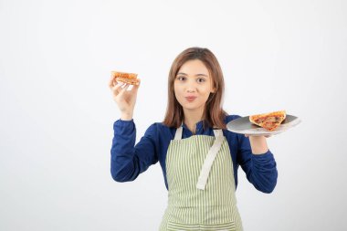 Beyaz arka planda pizza tutan önlüklü kadın aşçının portresi.