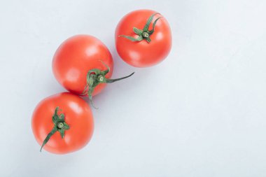 Beyaz arka planda üç tane taze domates.