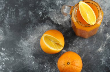 Mermer zemin üzerinde saf meyve suyu ve portakallar