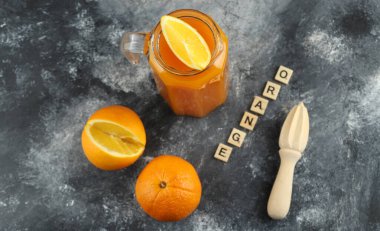 Saf meyve suyu, mermer zemin üzerinde merhem ve portakallar.