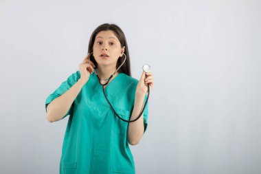 Genç ve güzel hemşire steteskop tutuyor ve duymaya çalışıyor.