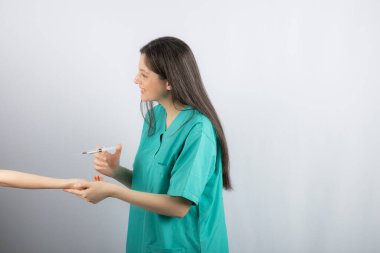 Yeşil üniformalı kadın doktor beyaz arka plandan vuruluyor.