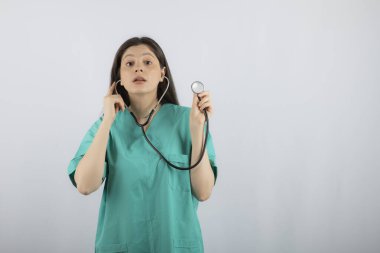 Genç ve güzel hemşire steteskop tutuyor ve duymaya çalışıyor.