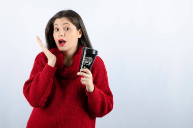 Elinde kahve tutan kırmızı kazaklı genç bir manken.