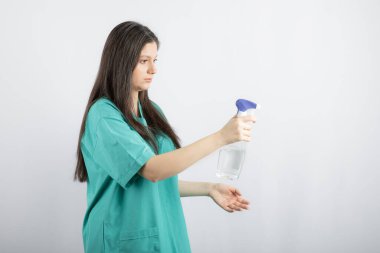 Dezenfektanı elinde tutan genç ve güzel bir hemşire.