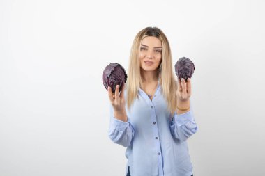 Beyaz arka planda mor lahana tutan mavi elbiseli güzel bir kadın.