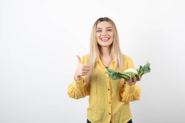 Karnabahar taşıyan güzel, gülümseyen bir kadın manken resmi.