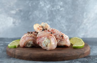 Tahta üzerinde limon dilimleri ile marine edilmiş tavuk bacağını kapat.