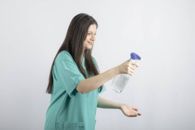 Gülümseyen genç hemşire diğerlerini dezenfekte ediyor.