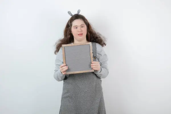 Imagem de uma menina bonita com síndrome de down segurando uma moldura — Fotografia de Stock