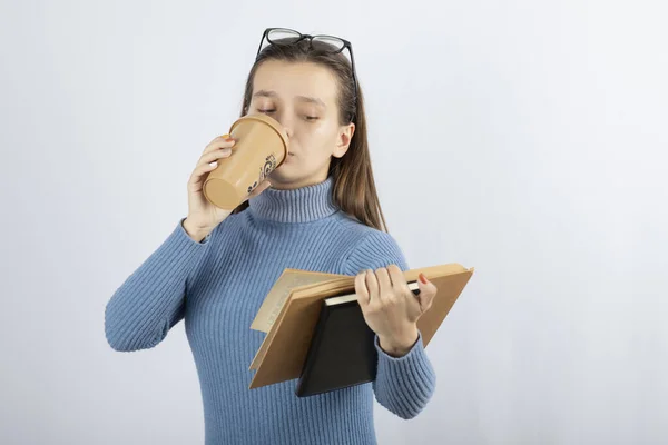 Retrato de uma menina em óculos lendo um livro com uma xícara de café — Fotografia de Stock