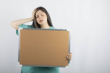 Elle tahtayı tutan yorgun genç hemşire.