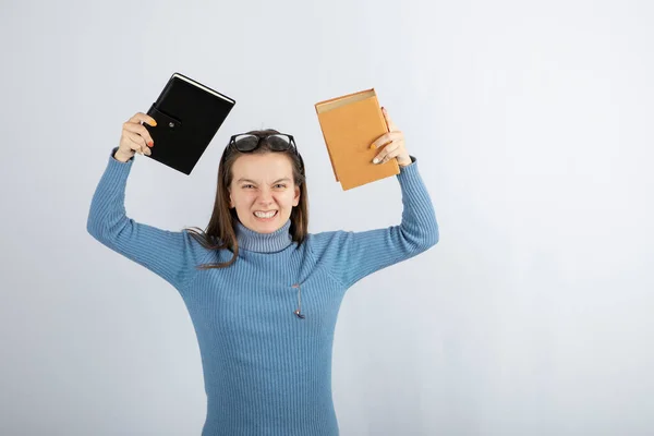 Retrato de uma menina em óculos segurando dois livros sobre fundo branco-cinza — Fotografia de Stock