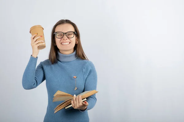 Retrato de uma menina em óculos segurando um livro e uma xícara de café — Fotografia de Stock