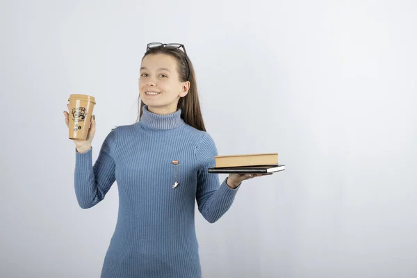 Retrato de uma menina em óculos segurando dois livros e uma xícara de café — Fotografia de Stock