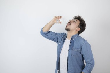 Çekici bir adamın cam bir kavanozdan ayakta durup içerken fotoğrafı.