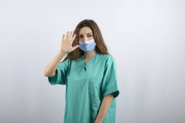 Yeşil üniformalı güzel hemşire tıbbi maske takıyor.