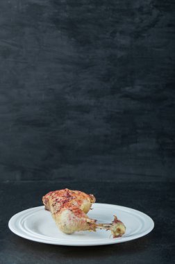 Siyah arka planda kızarmış tavuk olan beyaz bir tabak.