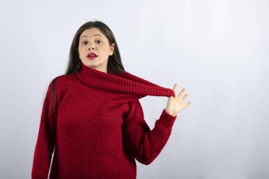 Kırmızı, sıcak süveter giymiş, ayakta duran ve poz veren genç bir kadının portresi.