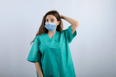 Yeşil üniformalı güzel hemşire tıbbi maske takıyor.