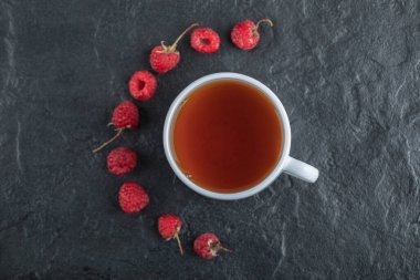 Siyah zemin üzerinde çay olan taze ahududu.