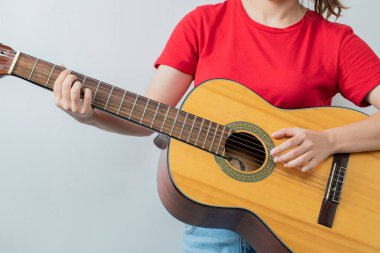 Kırmızı gömlekli, tahta gitarlı bir kadın model.