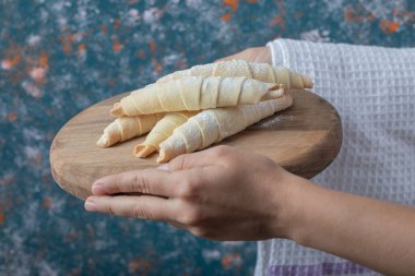 Elinde ahşap bir tahtanın üzerinde mutaki kurabiyeleri tutuyor.