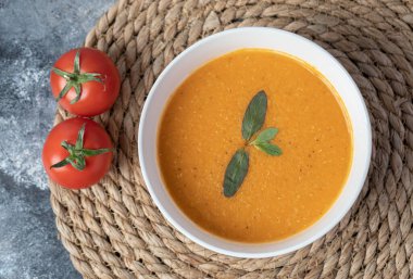 Beyaz bir kâse mermer kaplı domatesli mercimek çorbası.