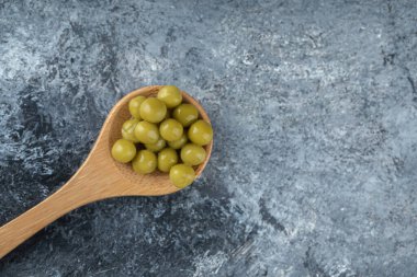 Kaşık, gri arkaplanda konserve zeytin.