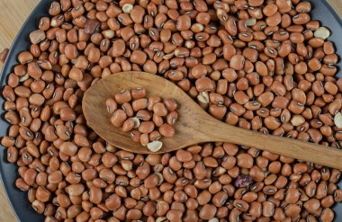 Tahta bir masada çiğ kahverengi fasulyeli koyu bir tabak.